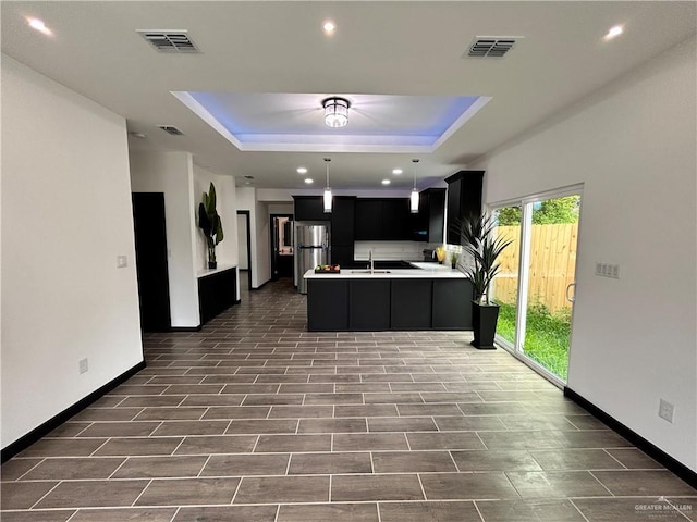 kitchen with visible vents, light countertops, freestanding refrigerator, dark cabinetry, and a raised ceiling