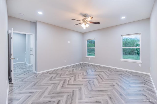 unfurnished room with ceiling fan, a healthy amount of sunlight, and light parquet flooring