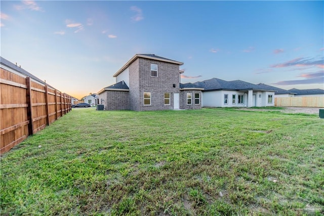 back house at dusk featuring a lawn