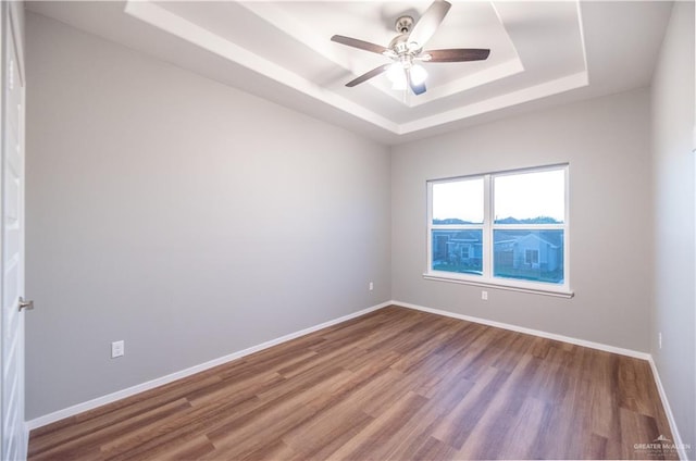 unfurnished room featuring hardwood / wood-style flooring, a raised ceiling, and ceiling fan