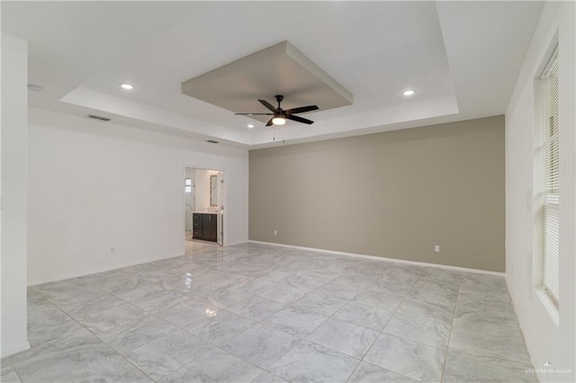 unfurnished room with ceiling fan and a raised ceiling