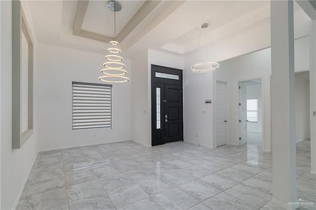 entrance foyer with a towering ceiling, a tray ceiling, and a chandelier