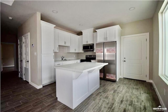 3131 Stark Rd, Weslaco, TX 78596 - kitchen with appliances with stainless steel finishes, white cabinetry, dark wood-style flooring, light countertops, and a kitchen island
