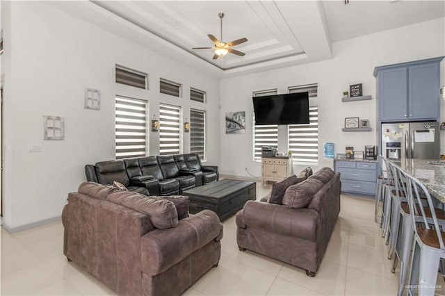 living room featuring light tile patterned floors, a raised ceiling, and ceiling fan