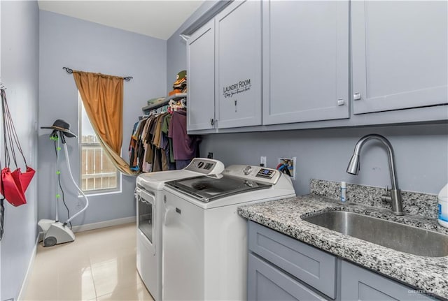 clothes washing area with washer and clothes dryer, light tile patterned flooring, cabinets, and sink