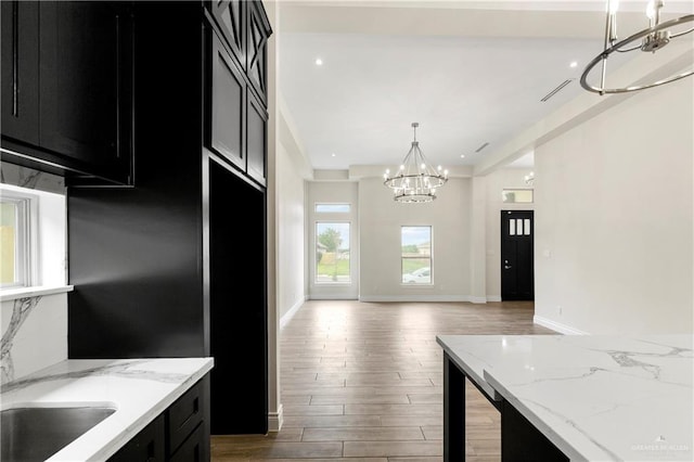 3317 Yellowhammer Ave, Mcallen, TX 78504 - kitchen with dark cabinets, a chandelier, light wood-style flooring, hanging light fixtures, and baseboards