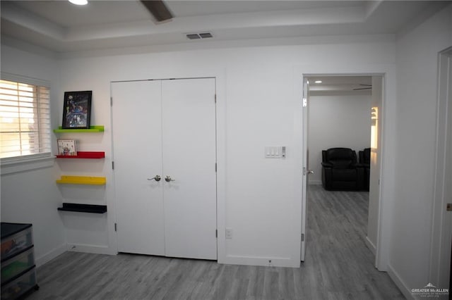 bedroom featuring a tray ceiling, hardwood / wood-style floors, and a closet