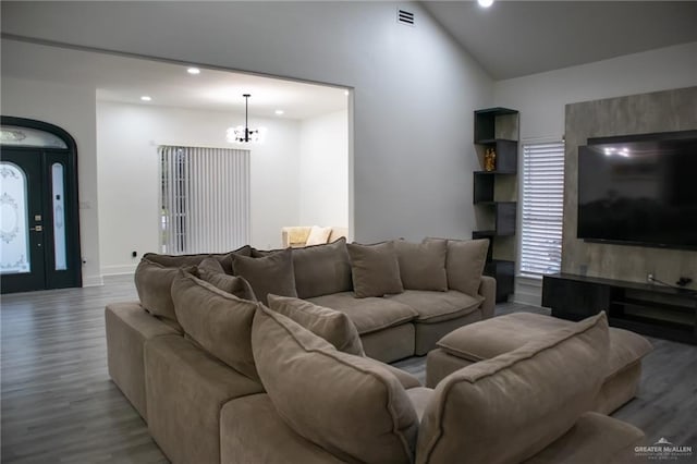 living room featuring lofted ceiling, an inviting chandelier, and light wood-type flooring