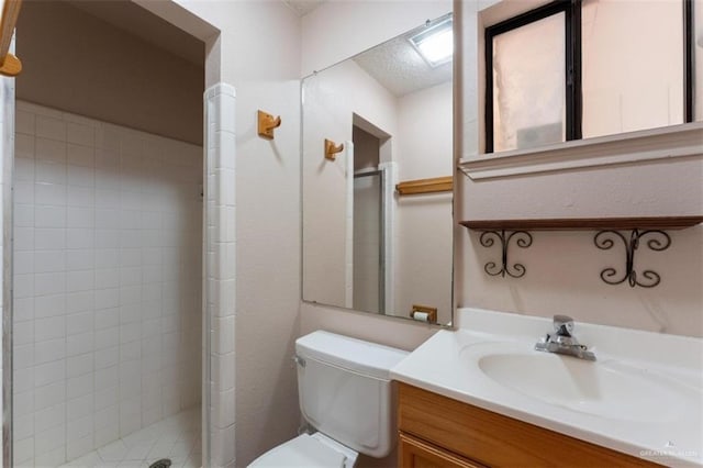 bathroom with vanity, toilet, and a tile shower