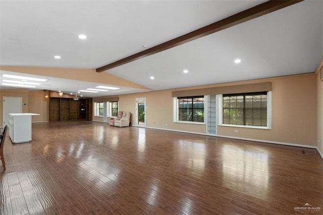 unfurnished living room featuring lofted ceiling with beams, dark wood-type flooring, and a healthy amount of sunlight