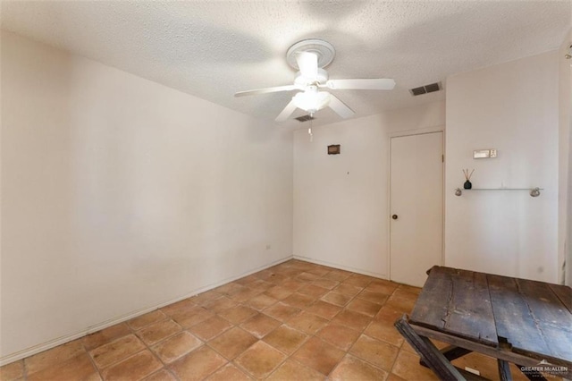 unfurnished room with ceiling fan and a textured ceiling