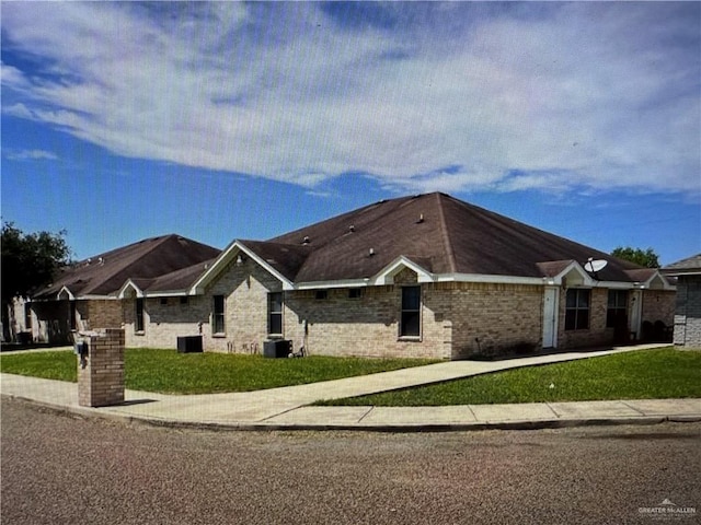 single story home with a front lawn, central AC, and brick siding