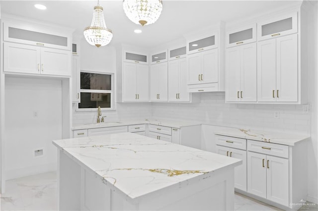 kitchen featuring hanging light fixtures, sink, white cabinets, and a center island