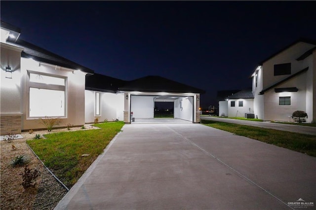 view of front of home featuring a garage, a yard, and cooling unit