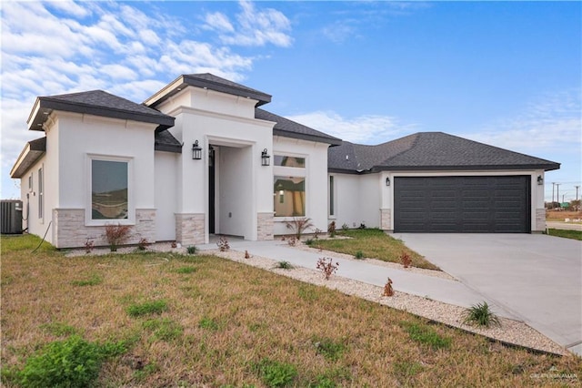 prairie-style home featuring central AC unit, a garage, and a front lawn