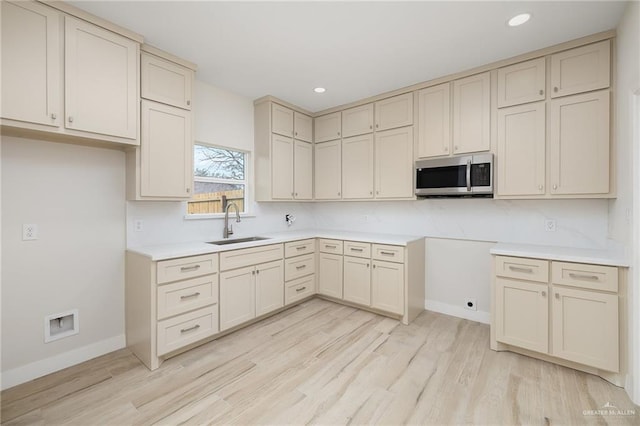 kitchen featuring cream cabinets, sink, and light wood-type flooring