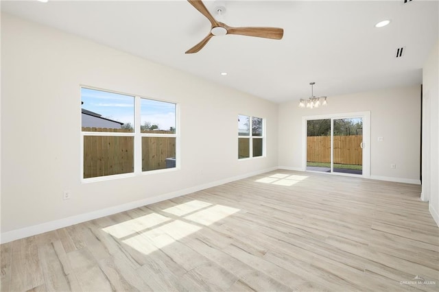 spare room with ceiling fan with notable chandelier and light hardwood / wood-style flooring