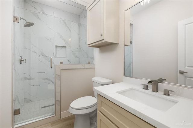 bathroom featuring vanity, hardwood / wood-style floors, a shower with door, and toilet