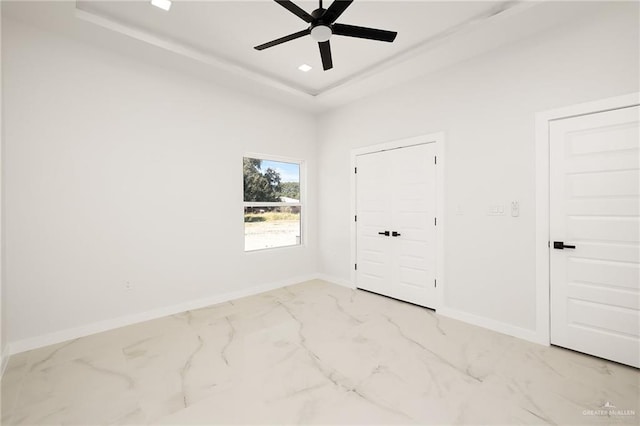 unfurnished bedroom featuring ceiling fan and a raised ceiling