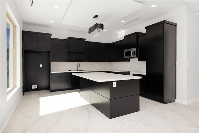 kitchen with a kitchen island, sink, hanging light fixtures, and a chandelier