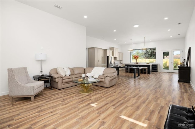 living room with light hardwood / wood-style floors, french doors, and beverage cooler