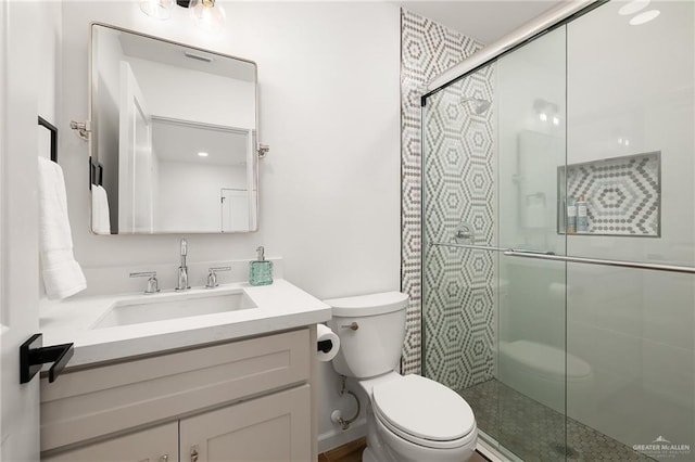 bathroom featuring vanity, a shower with door, and toilet