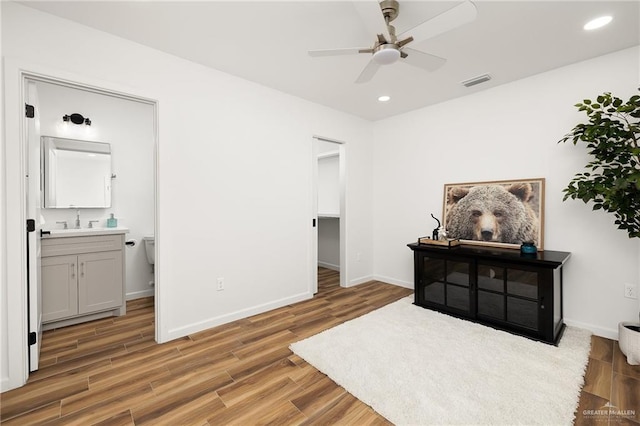 interior space featuring hardwood / wood-style floors, a spacious closet, ceiling fan, ensuite bathroom, and sink