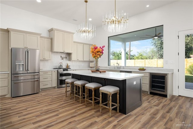 kitchen featuring a breakfast bar, beverage cooler, a kitchen island, stainless steel appliances, and decorative backsplash