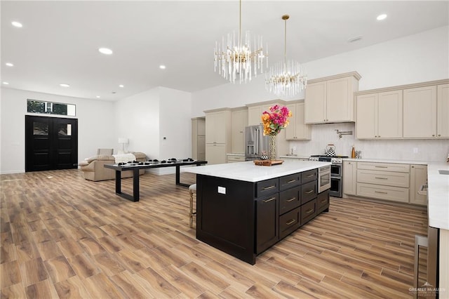 kitchen featuring stainless steel appliances, cream cabinets, decorative light fixtures, backsplash, and a kitchen island