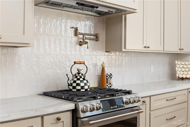 kitchen featuring tasteful backsplash, custom exhaust hood, light stone countertops, and stainless steel gas range