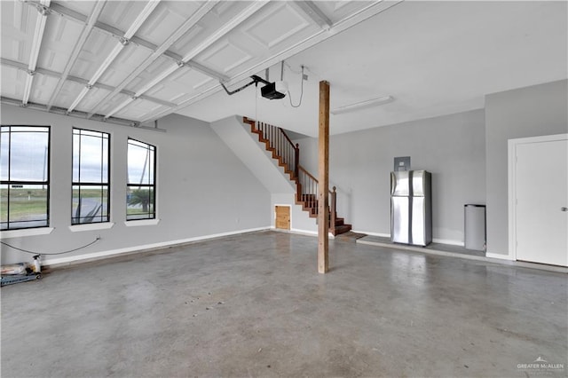 garage featuring baseboards, a garage door opener, and freestanding refrigerator