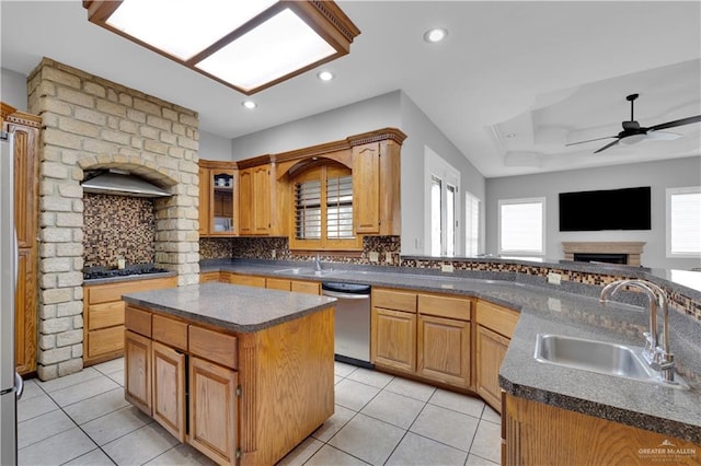 kitchen with a center island with sink, dark countertops, decorative backsplash, stainless steel dishwasher, and a sink