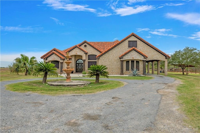 french provincial home with driveway and brick siding