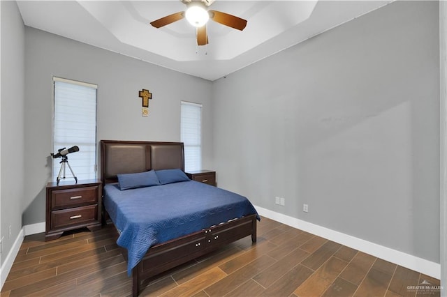 bedroom featuring baseboards, a raised ceiling, a ceiling fan, and wood tiled floor