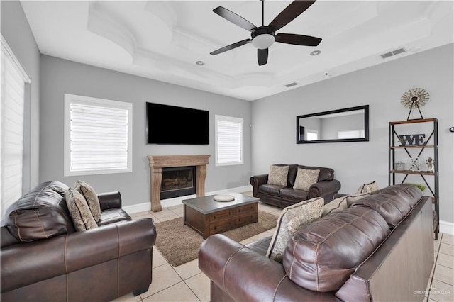 living area with light tile patterned flooring, a premium fireplace, visible vents, baseboards, and a raised ceiling