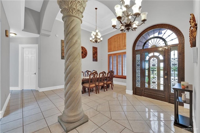 entryway featuring decorative columns, a chandelier, arched walkways, and light tile patterned flooring