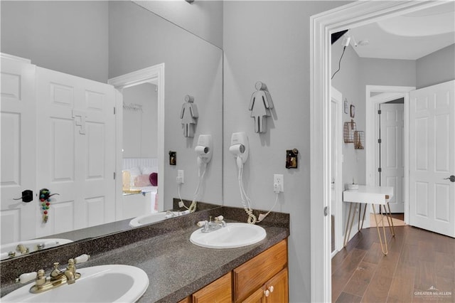 full bathroom with double vanity, a sink, and wood finished floors