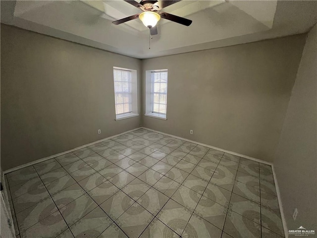 spare room with ceiling fan and a tray ceiling