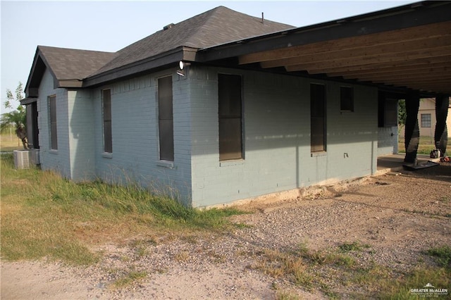 view of side of home with central AC and a carport