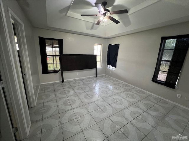 spare room featuring a healthy amount of sunlight, ceiling fan, and a tray ceiling