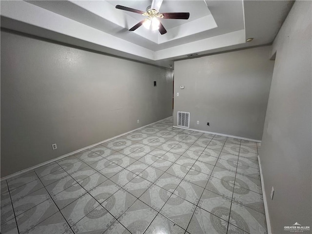 empty room with a raised ceiling and ceiling fan