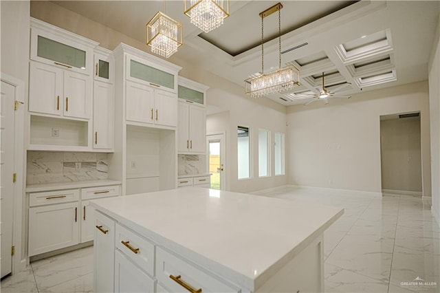 kitchen featuring white cabinetry, a center island, coffered ceiling, decorative light fixtures, and ceiling fan with notable chandelier