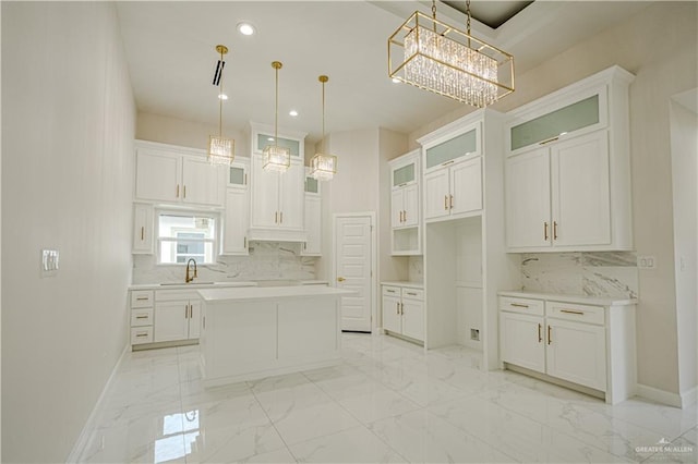 kitchen featuring sink, decorative light fixtures, a chandelier, a center island, and white cabinetry