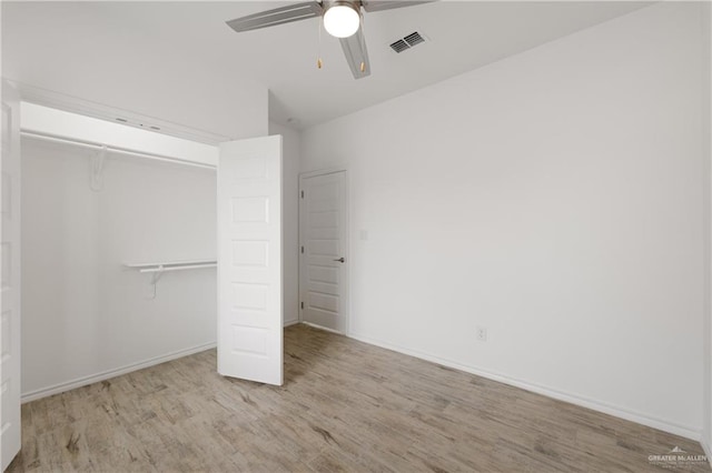 unfurnished bedroom with vaulted ceiling, a closet, light hardwood / wood-style flooring, and ceiling fan