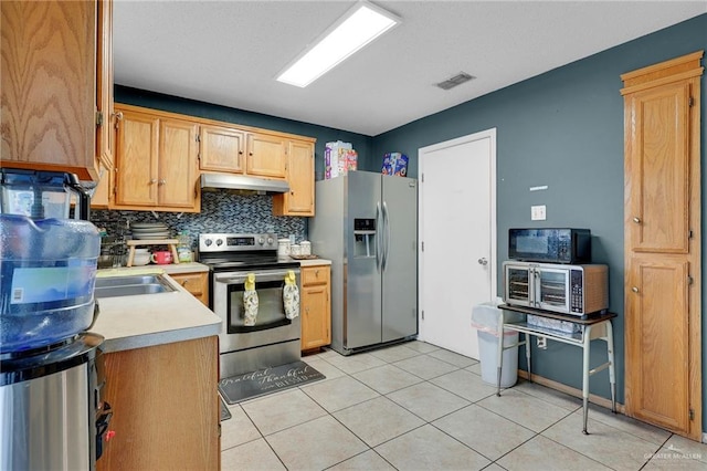 1604 E Kennedy Ave, Alton, TX 78573 - kitchen with appliances with stainless steel finishes, under cabinet range hood, light countertops, decorative backsplash, and light tile patterned floors