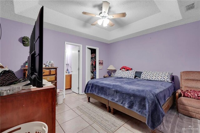1604 E Kennedy Ave, Alton, TX 78573 - bedroom with light tile patterned floors, a textured ceiling, a ceiling fan, a spacious closet, and a raised ceiling