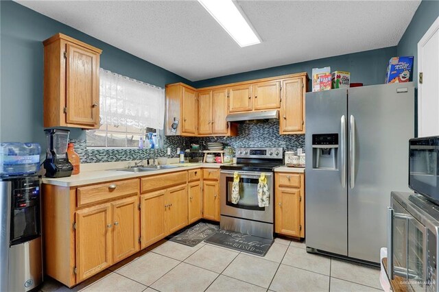 1604 E Kennedy Ave, Alton, TX 78573 - kitchen featuring stainless steel appliances, under cabinet range hood, light countertops, tasteful backsplash, and light tile patterned flooring