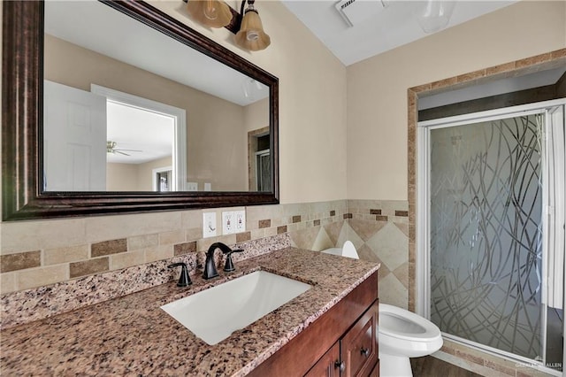 318 E 2nd Ave, Elsa, TX 78543 - bathroom with vanity, toilet, a shower stall, tile walls, and a ceiling fan