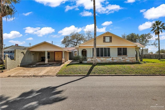 318 E 2nd Ave, Elsa, TX 78543 - view of front of home featuring stone siding, driveway, and a carport