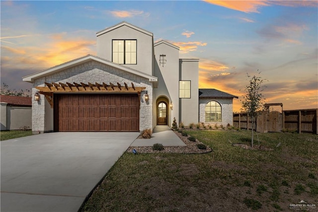 view of front of home with stucco siding, a lawn, driveway, fence, and a garage